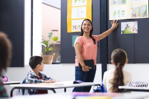 biracial young female teacher instructs attentive students classroom